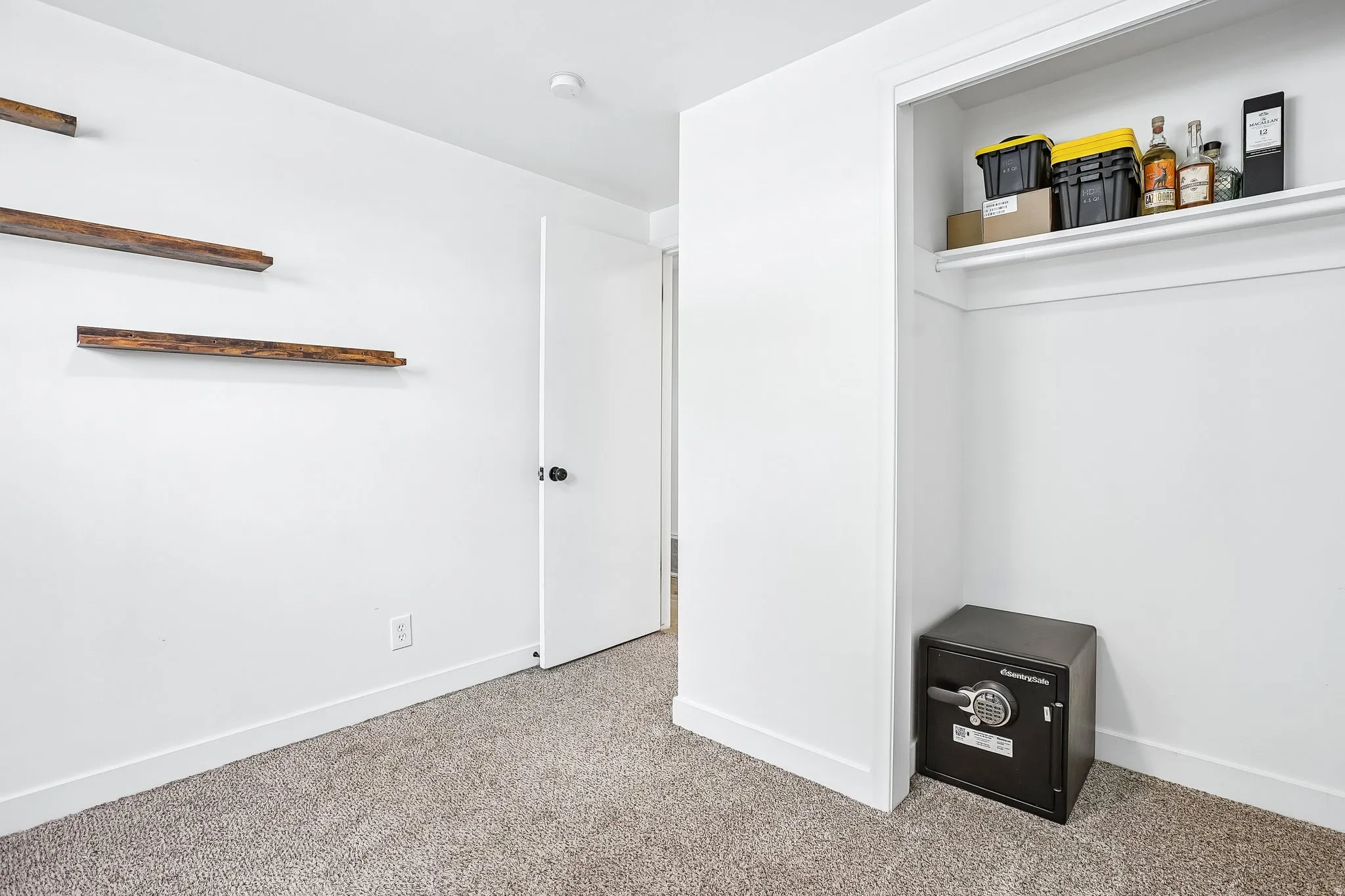 Room featuring light gray carpet flooring, white painted walls, and a white interior door with a black doorknob