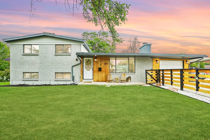 Split-level residence featuring a gray brick facade and contrasting wood paneling