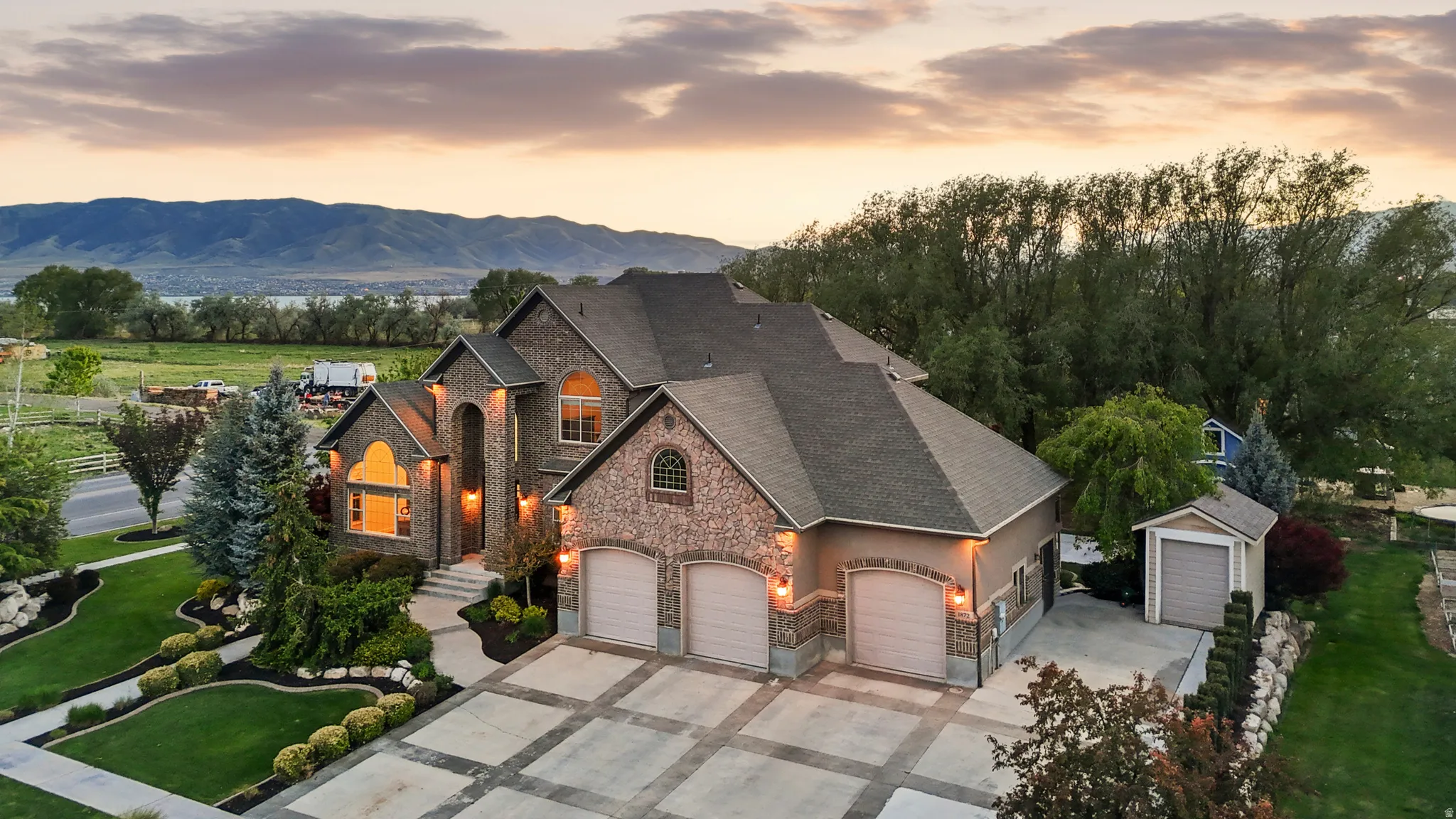 Stately stone and stucco residence featuring an integrated three-car garage and a paved driveway