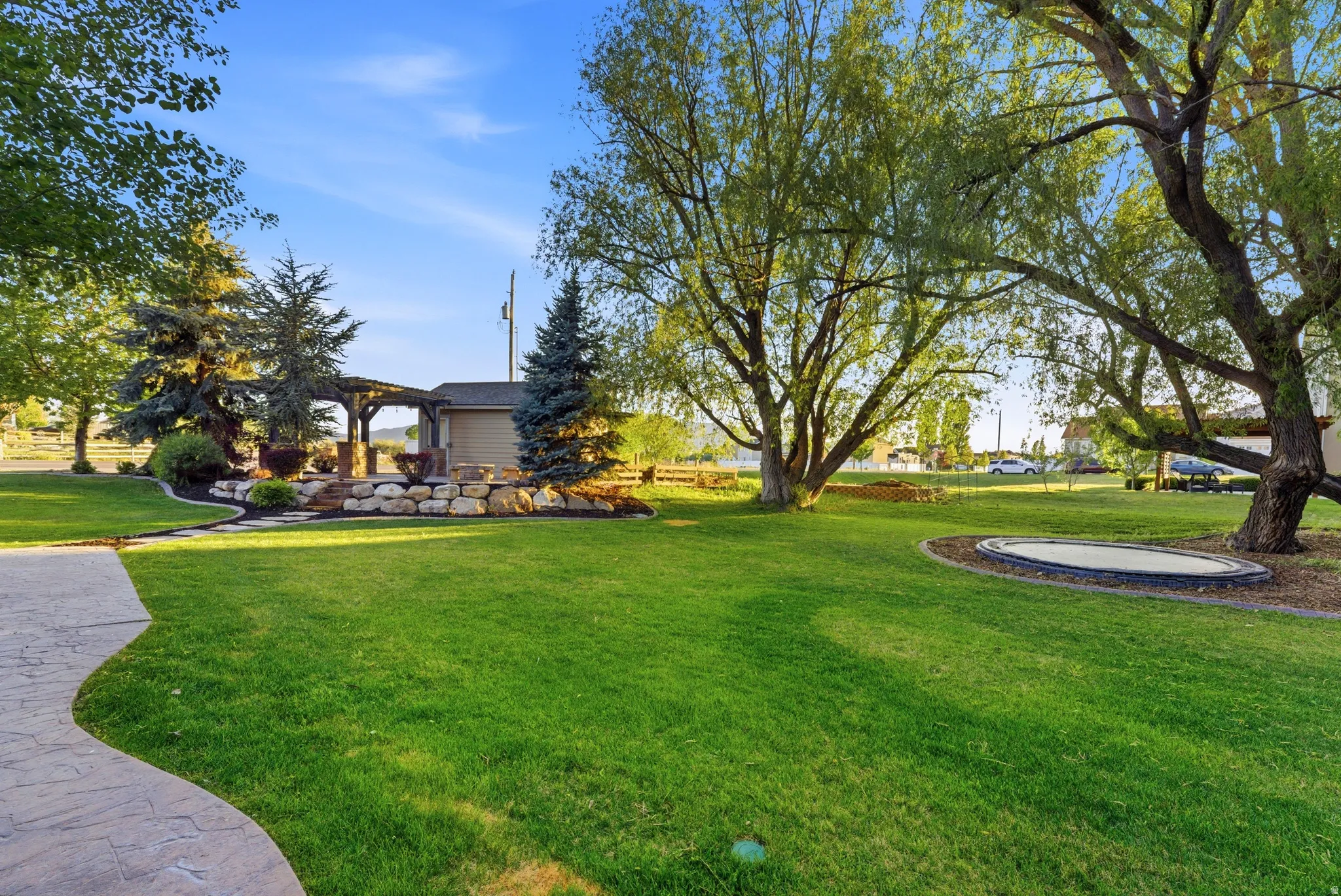 Expansive green lawn with mature trees and a stamped concrete pathway