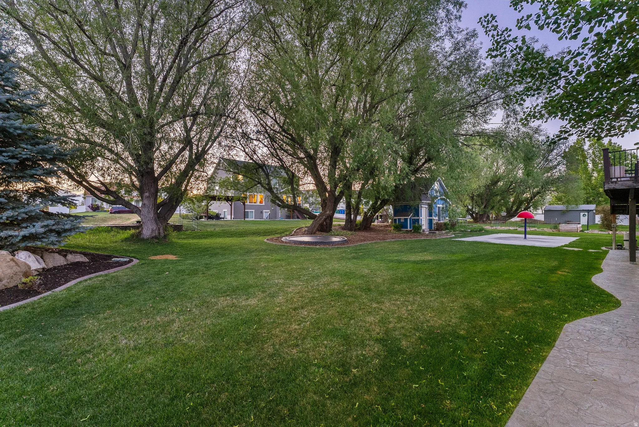 Expansive lawn with mature trees and a curvilinear stamped concrete patio