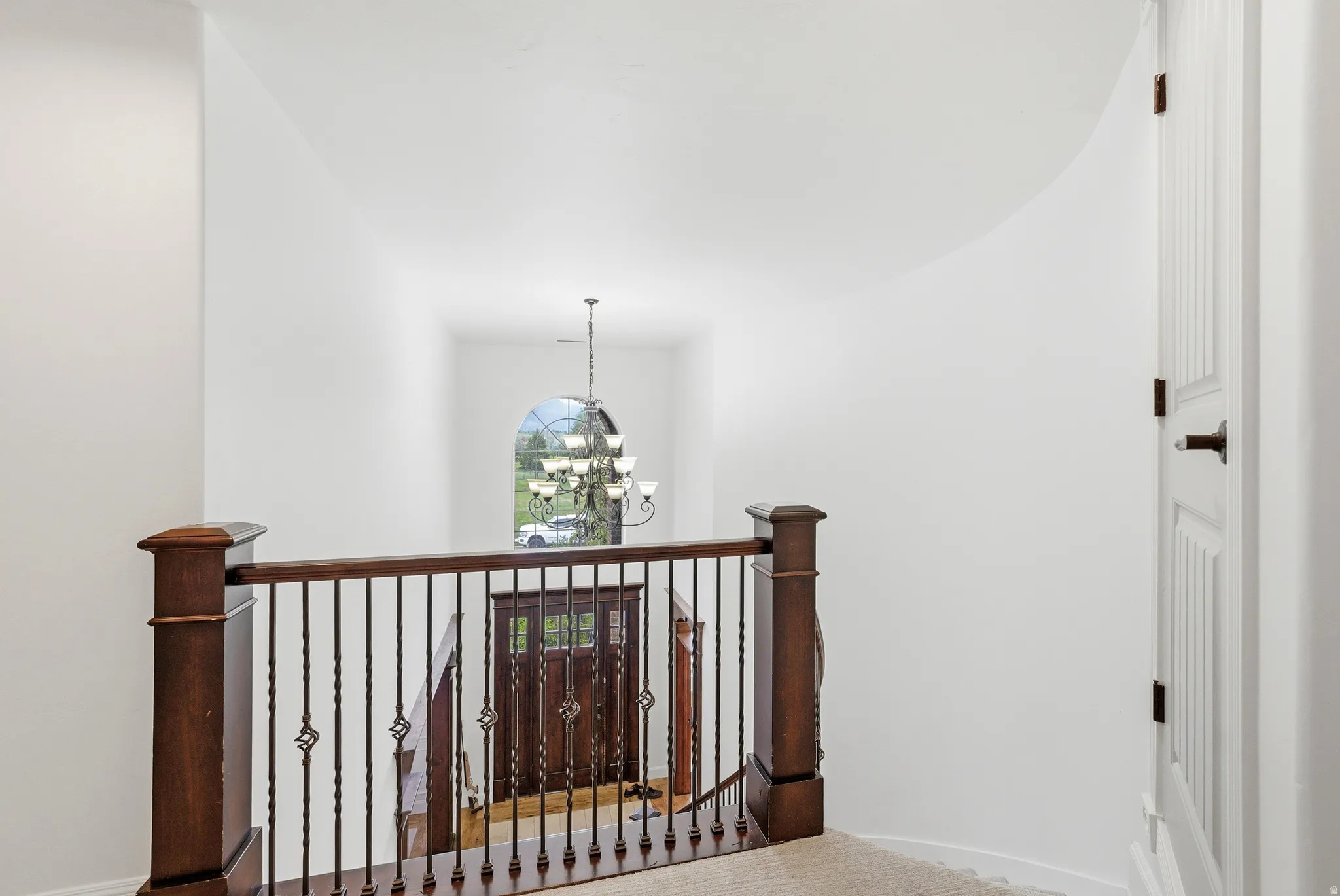 Entryway featuring a dark wood double door with decorative glass, an arched window, and a chandelier