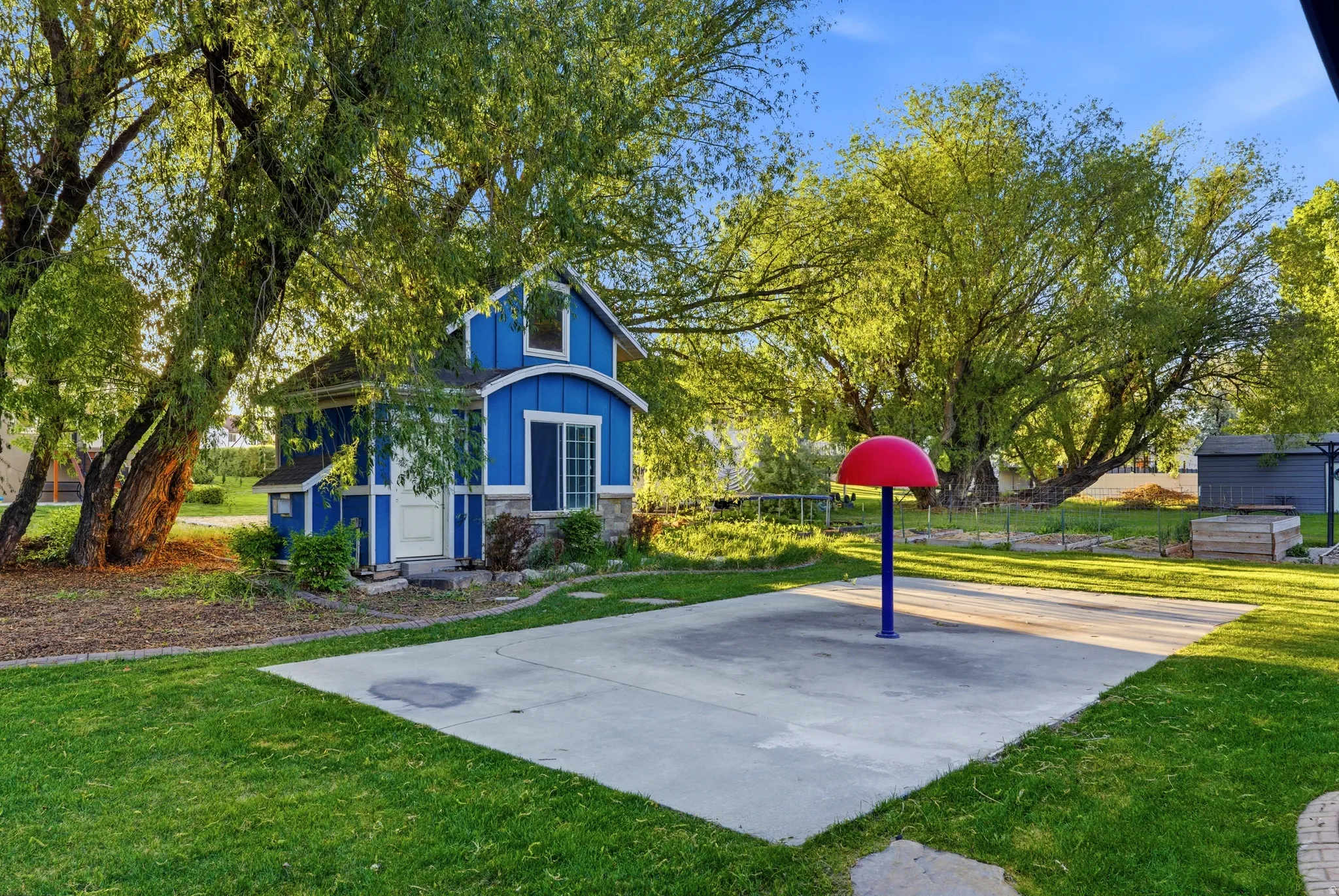 Expansive green lawn with a concrete pad and a blue play structure featuring a red top