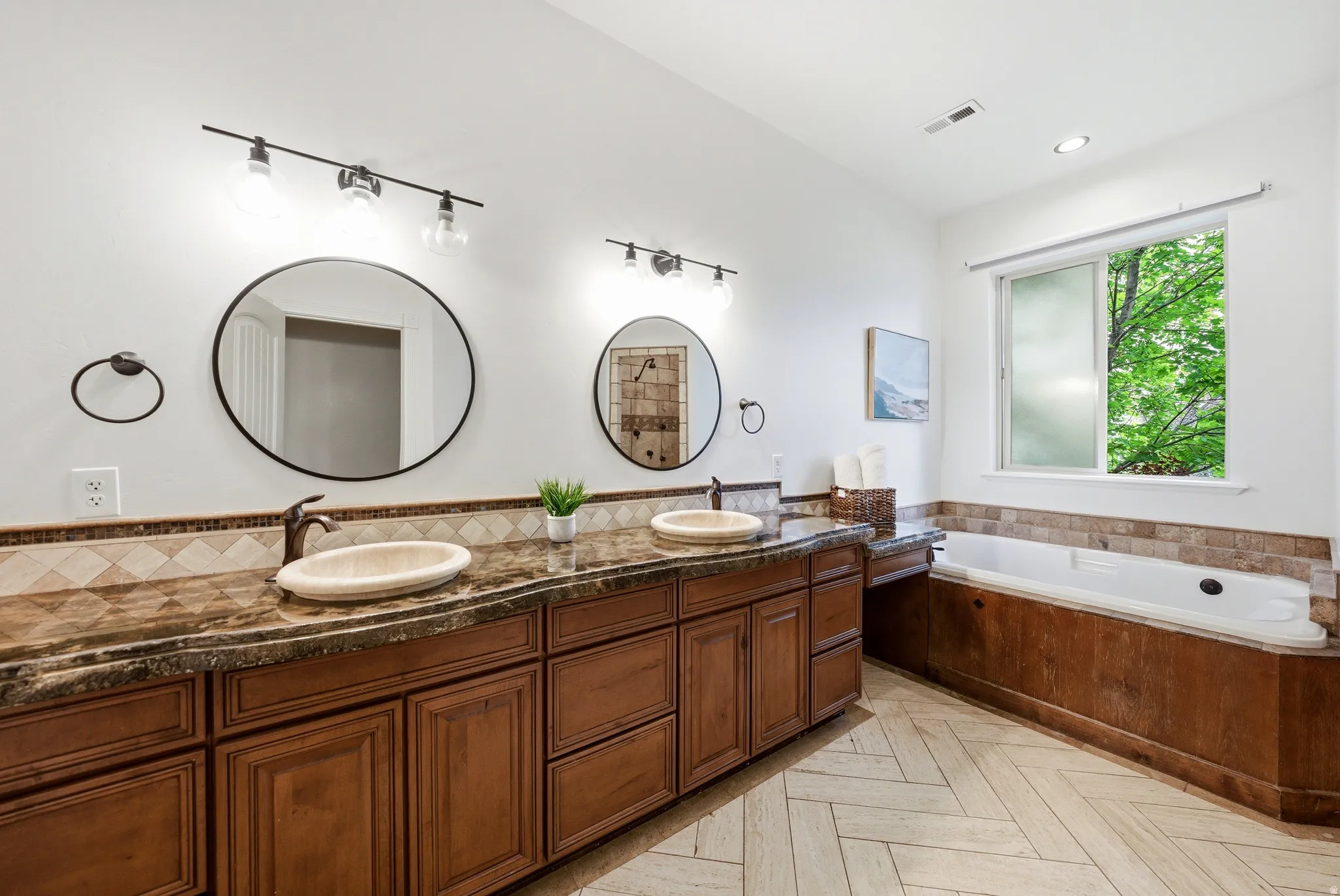 Dual vanity with vessel sinks, ornate bronze faucets, and a speckled countertop