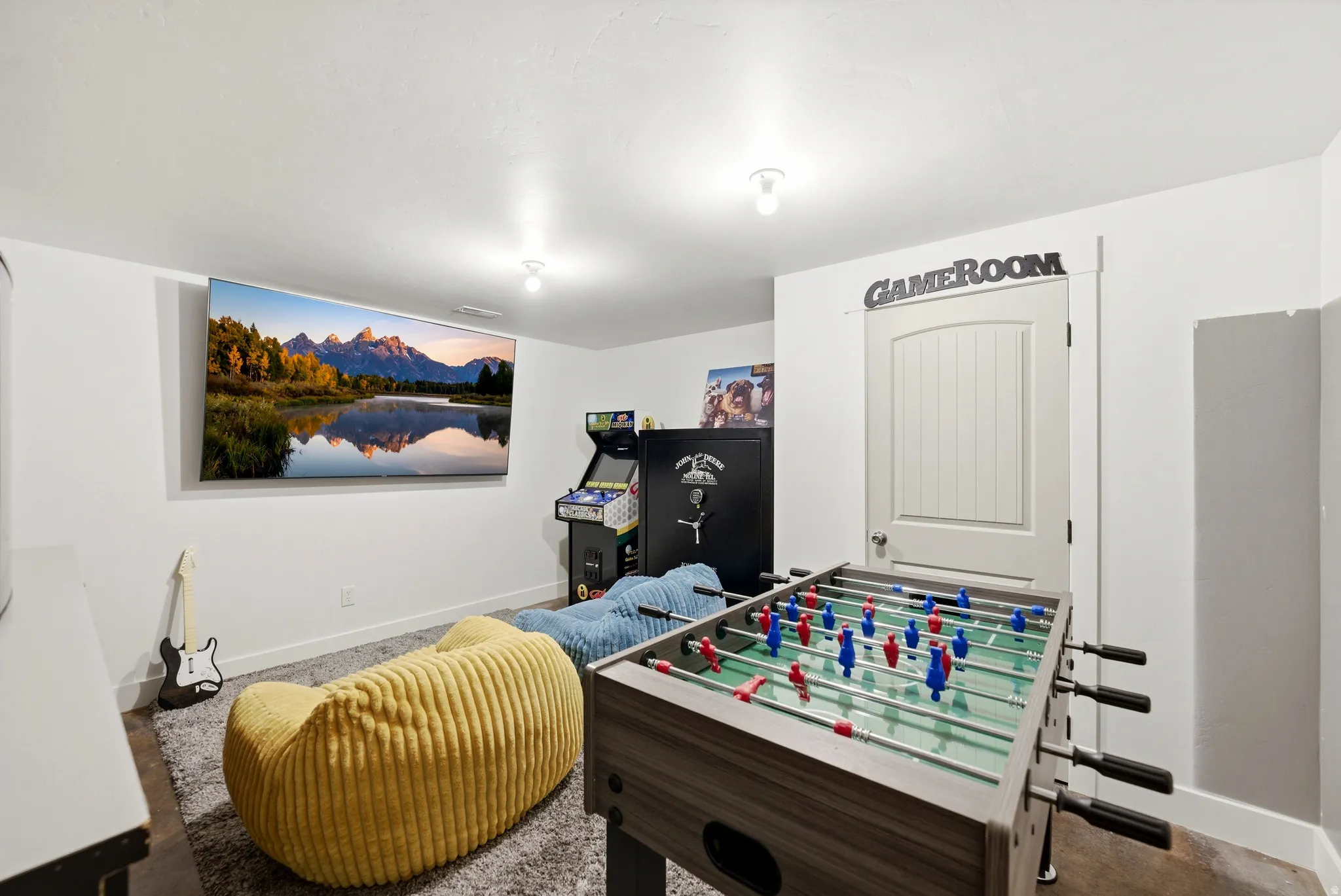 Spacious room featuring light-colored walls, a wall-mounted screen, and overhead lighting