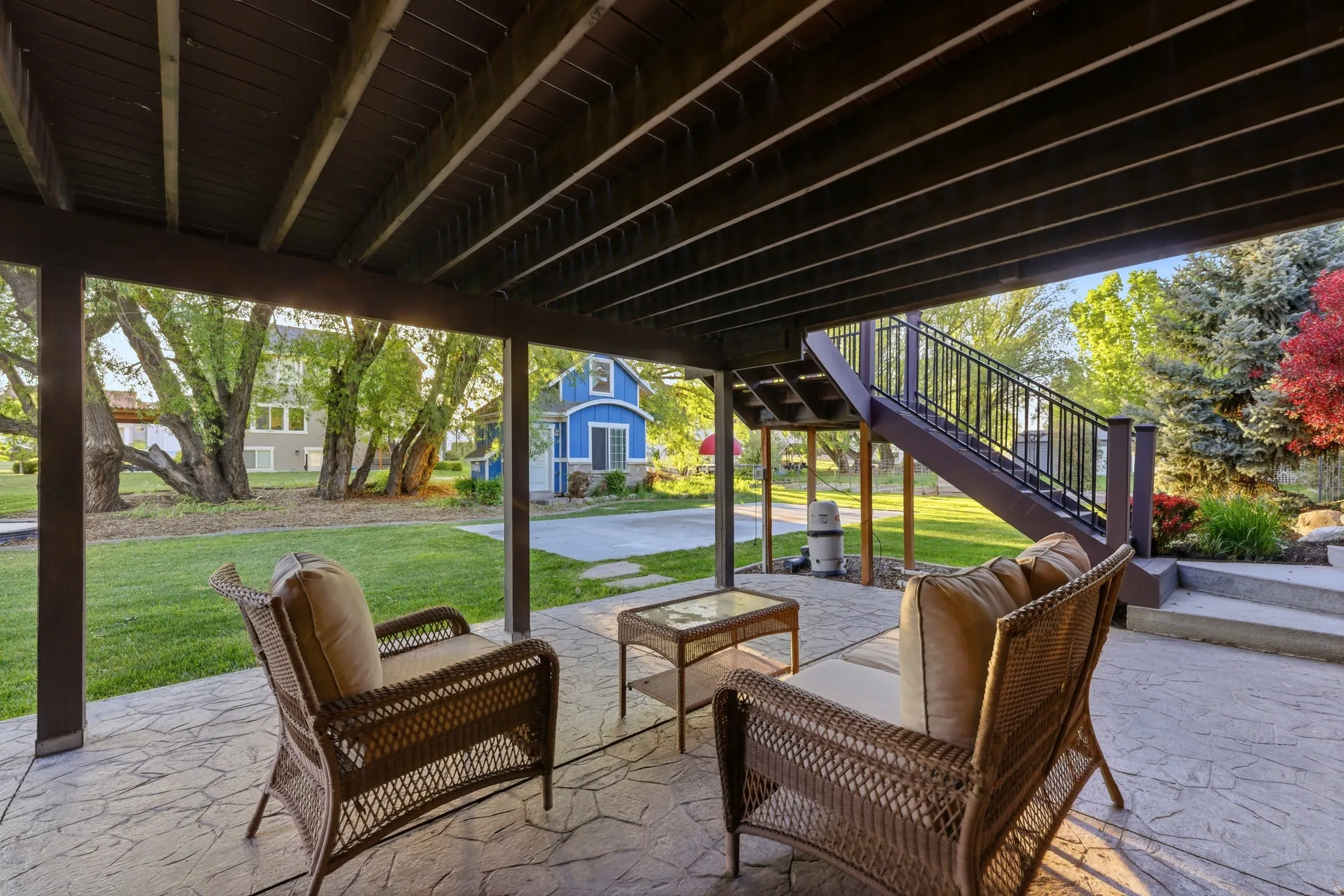 Covered patio with stamped concrete flooring, supported by a finished wooden beam structure