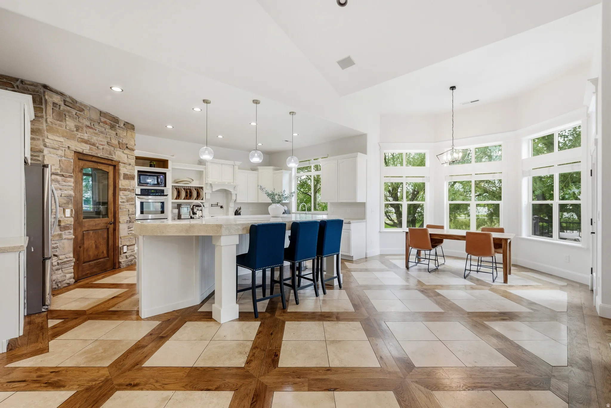 Spacious kitchen featuring white cabinetry, integrated stainless steel appliances, and an expansive center island with pendant lighting
