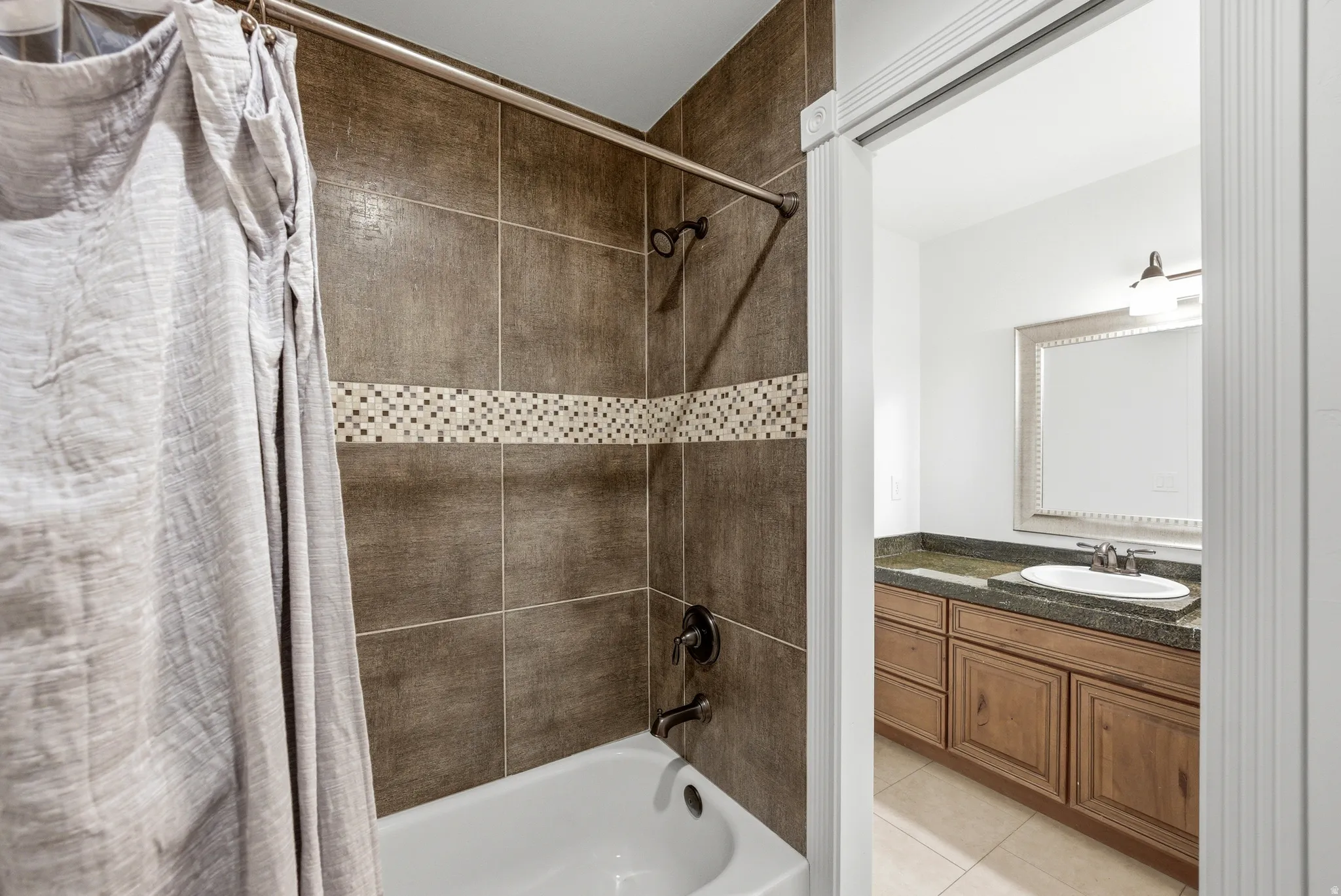 Bathroom featuring a shower/tub combination with ceramic tile surround and decorative mosaic accent