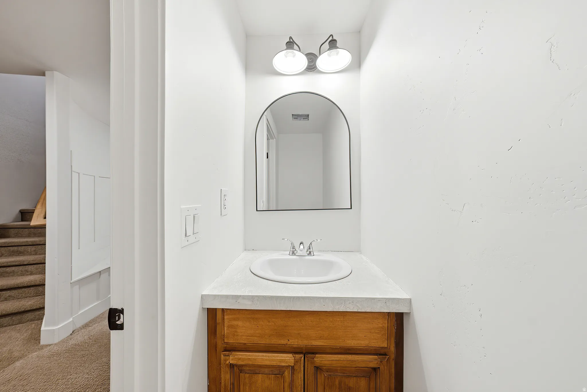 Compact vanity featuring a white countertop with an integrated sink and a wood-finish cabinet