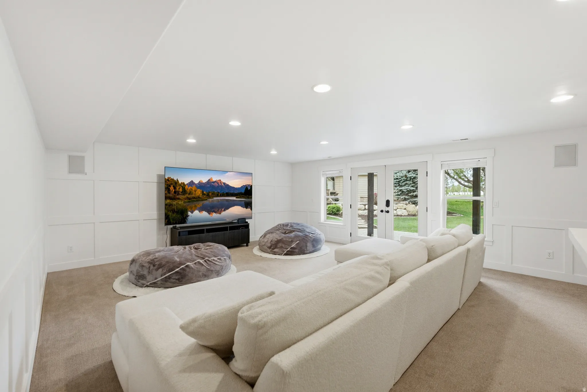 Carpeted recreation room featuring white paneled walls, recessed lighting, and built-in speakers