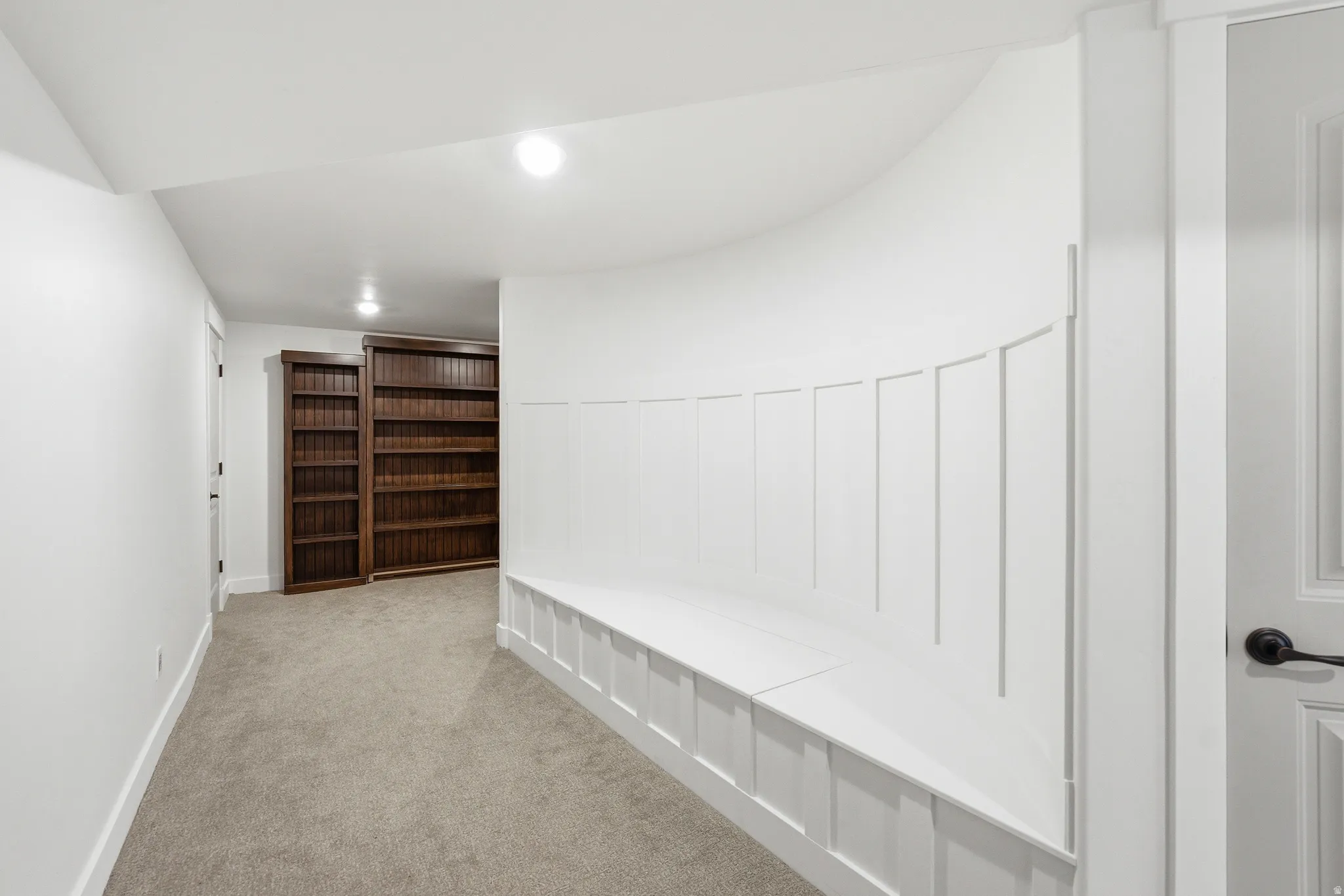 Curved built-in bench seating with wainscoting detail, complemented by recessed lighting and neutral carpeting