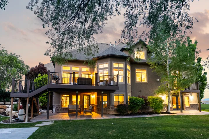 Spacious multi-level property with an expansive lawn, featuring a main-level deck, a lower-level patio, and a secondary upper-level balcony