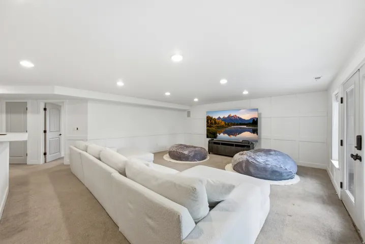 Spacious entertainment room featuring recessed lighting, paneled accent wall, neutral carpet flooring, and double French doors