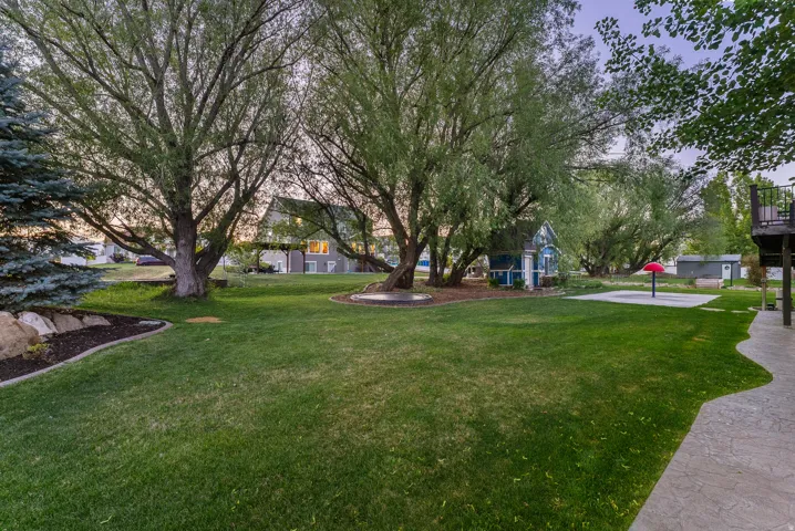 Expansive lawn with mature trees and a curvilinear stamped concrete patio