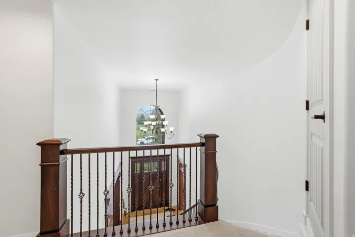 Entryway featuring a dark wood double door with decorative glass, an arched window, and a chandelier
