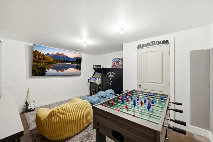 Spacious room featuring light-colored walls, a wall-mounted screen, and overhead lighting
