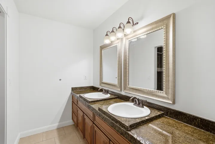 Dual vanity with under-mount sinks, dark bronze fixtures, and stone countertops
