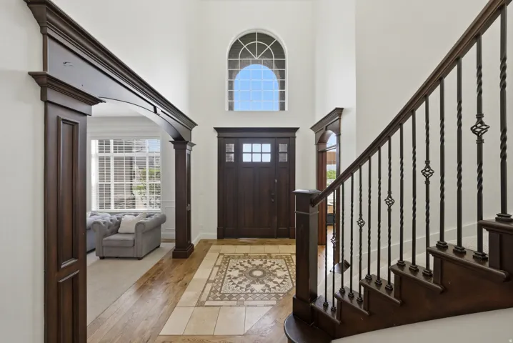 Grand entryway featuring a two-story ceiling, arched window, and a dark wood-finish front door