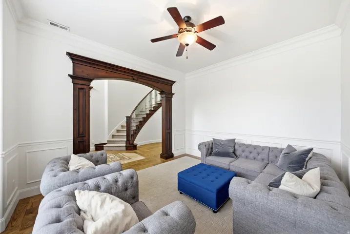 Living space featuring a detailed wooden archway, crown molding, and wainscoting