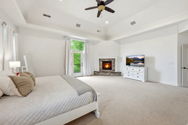 Spacious bedroom with a stone-clad fireplace and a balcony door