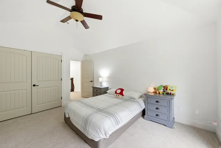 Carpeted bedroom with a vaulted ceiling and a ceiling fan