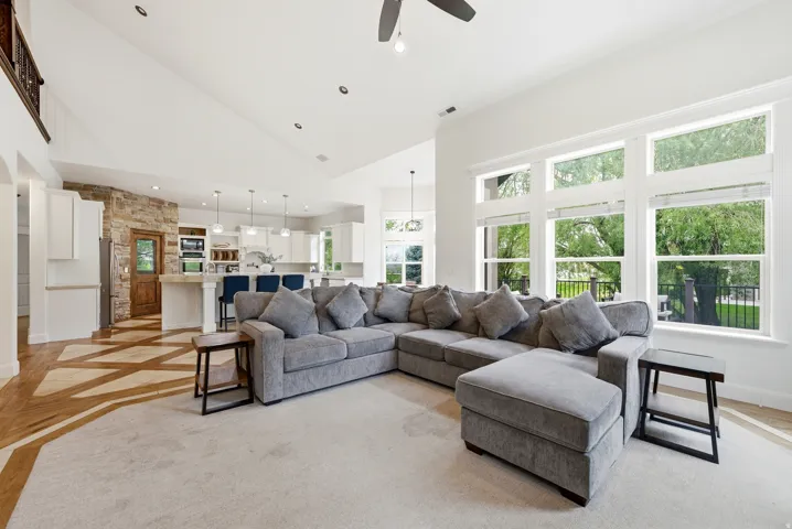 Spacious open-concept living area featuring a vaulted ceiling and an abundance of natural light from multiple large windows