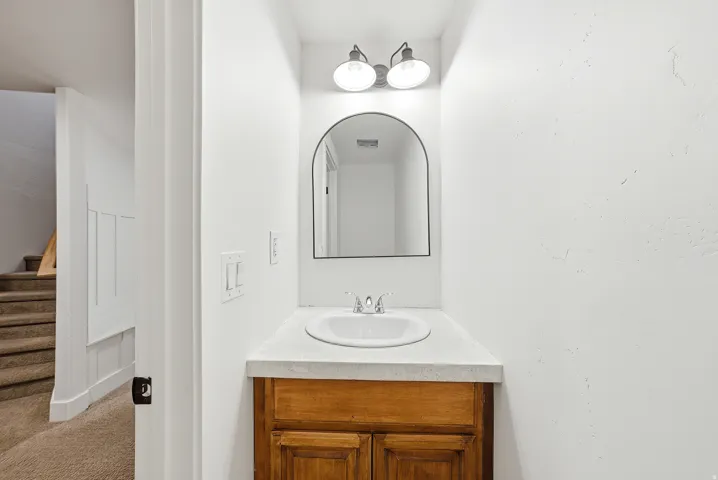Compact vanity featuring a white countertop with an integrated sink and a wood-finish cabinet