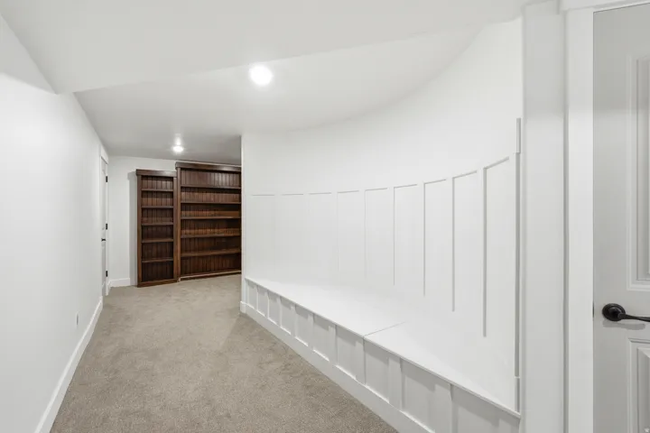 Curved built-in bench seating with wainscoting detail, complemented by recessed lighting and neutral carpeting