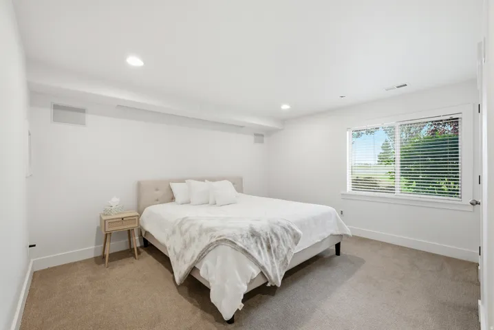 Bright room featuring recessed lighting, a window with horizontal blinds, white trim, and light-toned carpet flooring