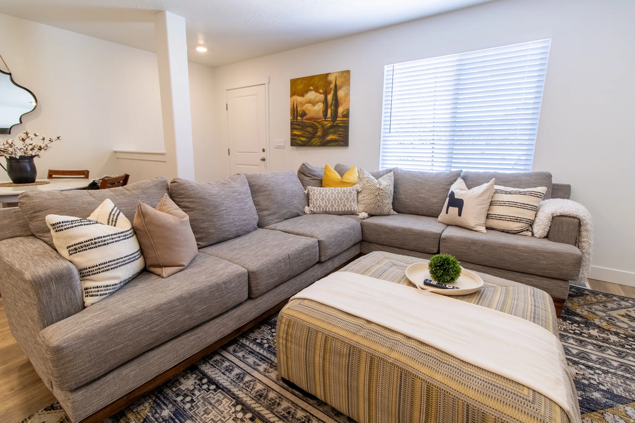 Bright open-concept living space featuring premium laminate flooring, recessed lighting, and a large window with high end vinyl  blinds that brings in plenty of natural light