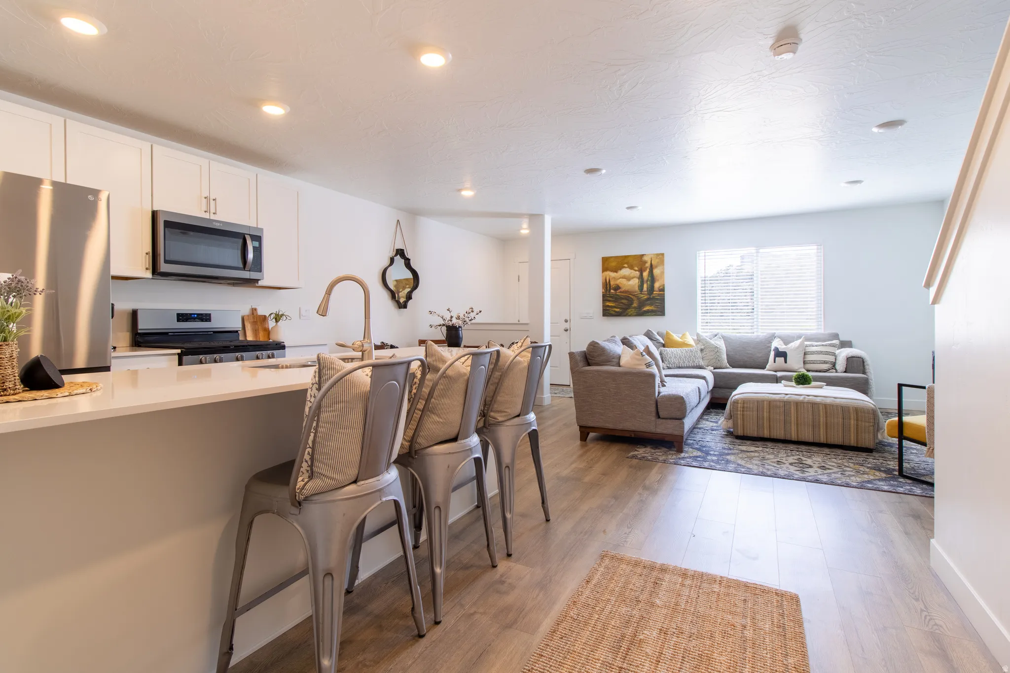 Open-concept living space featuring   quartz countertops, breakfast bar, stainless steel appliances, generous living room, recessed lighting, and premium laminate flooring