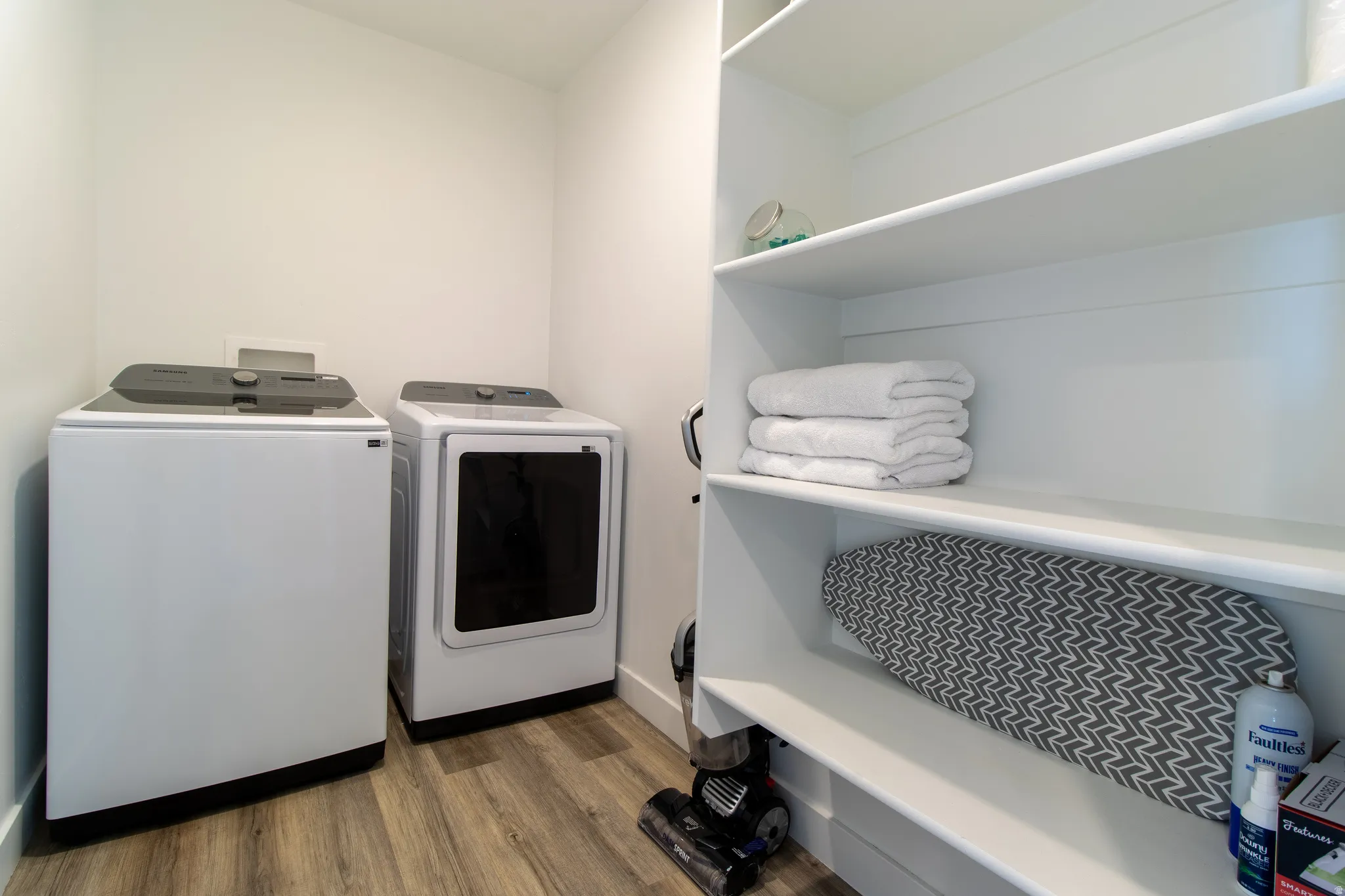 Large laundry room with  premium laminate flooring, new washer and dryer, and built-in shelving