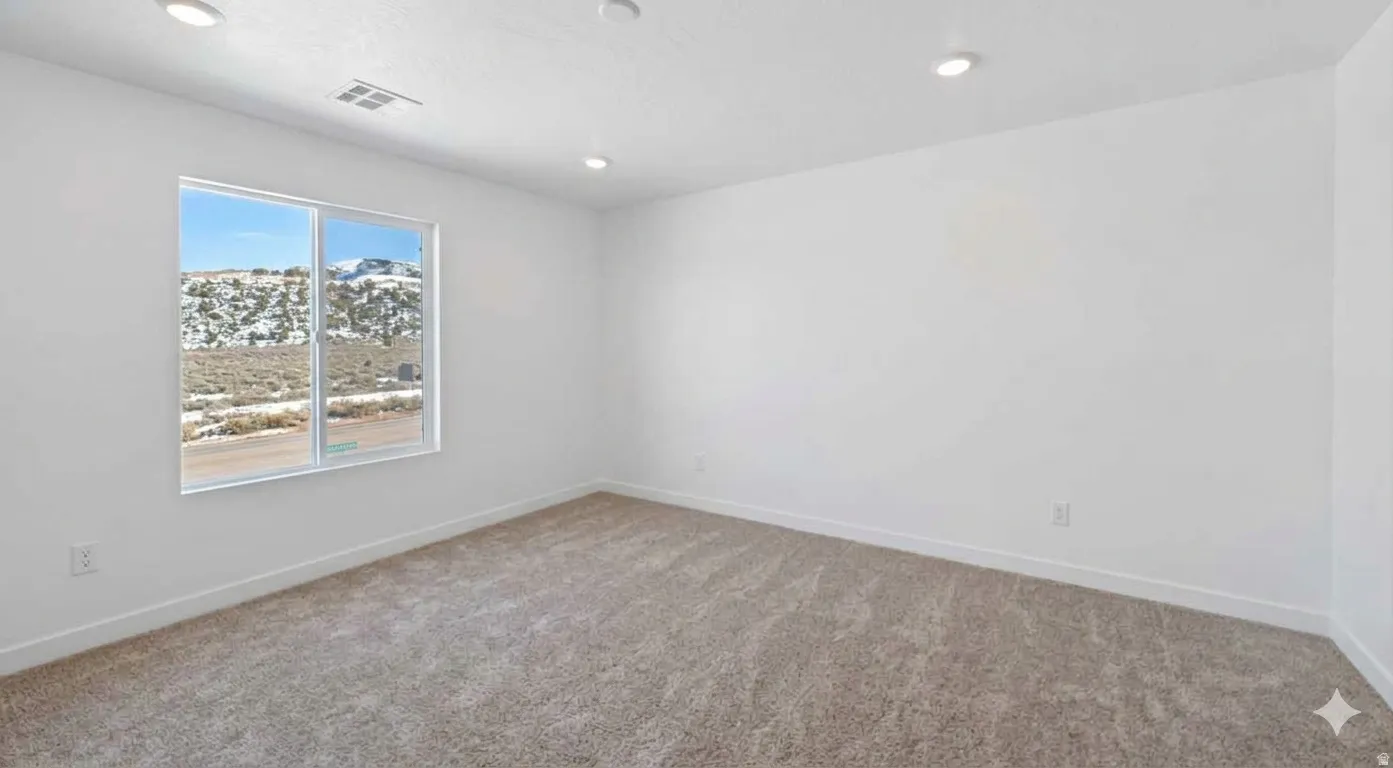Spacious primary bedroom featuring recessed lighting, a large window that fills the space with abundant natural light, a private ensuite bath, and neutral carpet flooring