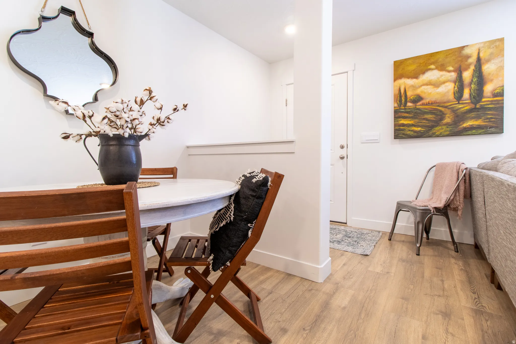 Dining area, front door behind pony wall  with extensive baseboard and premium laminate flooring