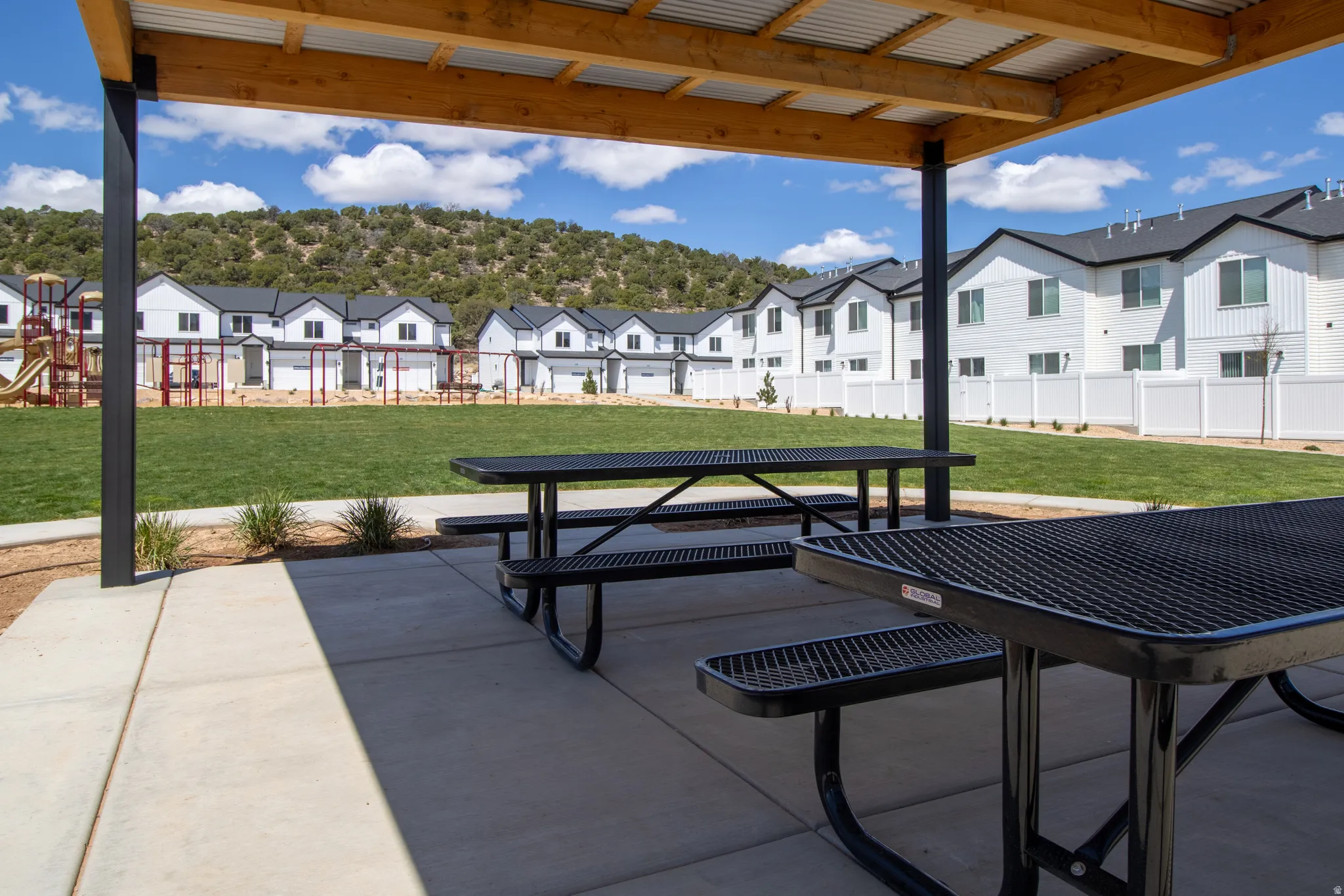 Covered patio area with concrete flooring and integrated metal picnic tables