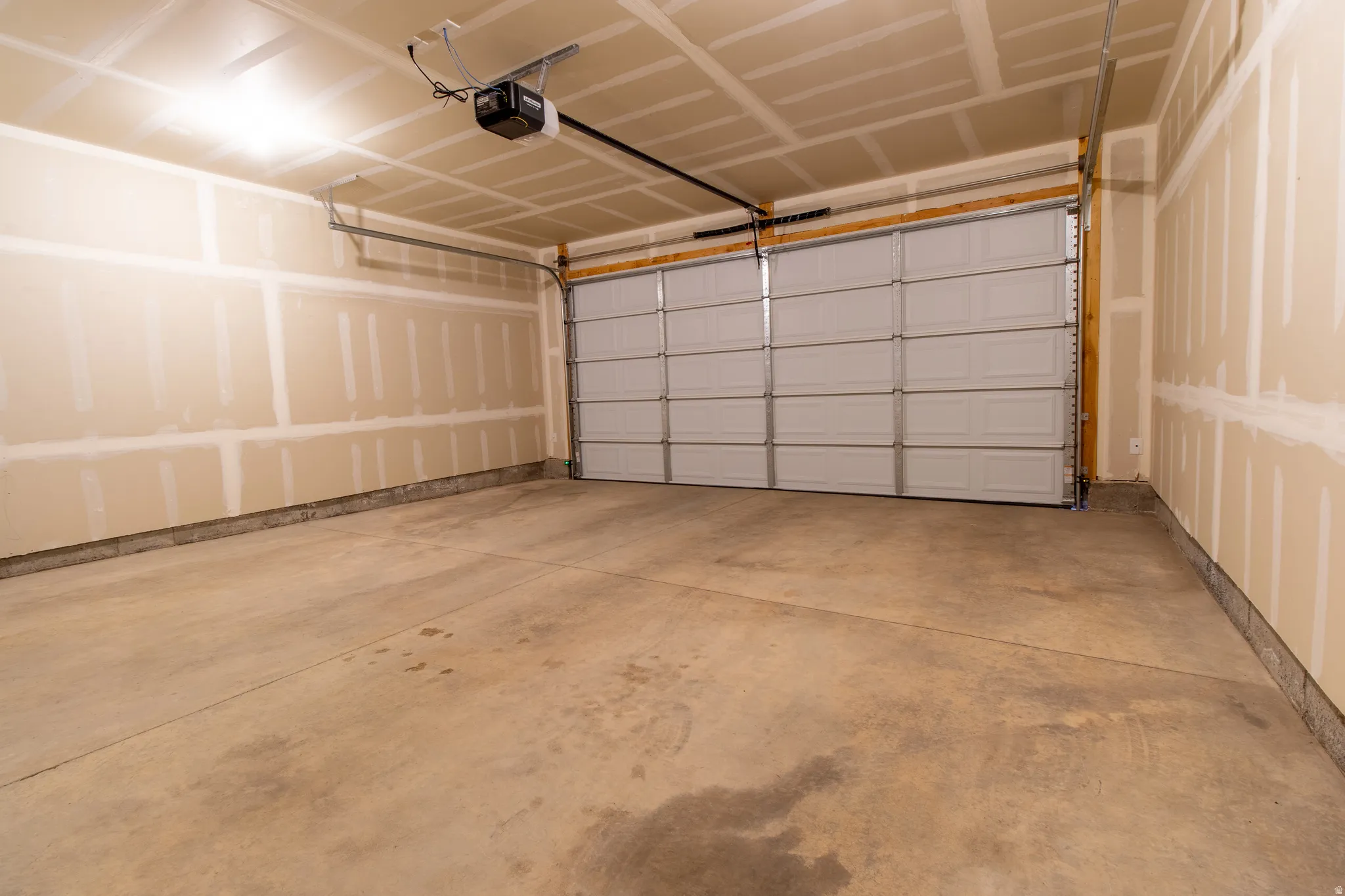 Spacious two-car garage featuring a concrete floor, an overhead garage door, and an automatic garage door opener