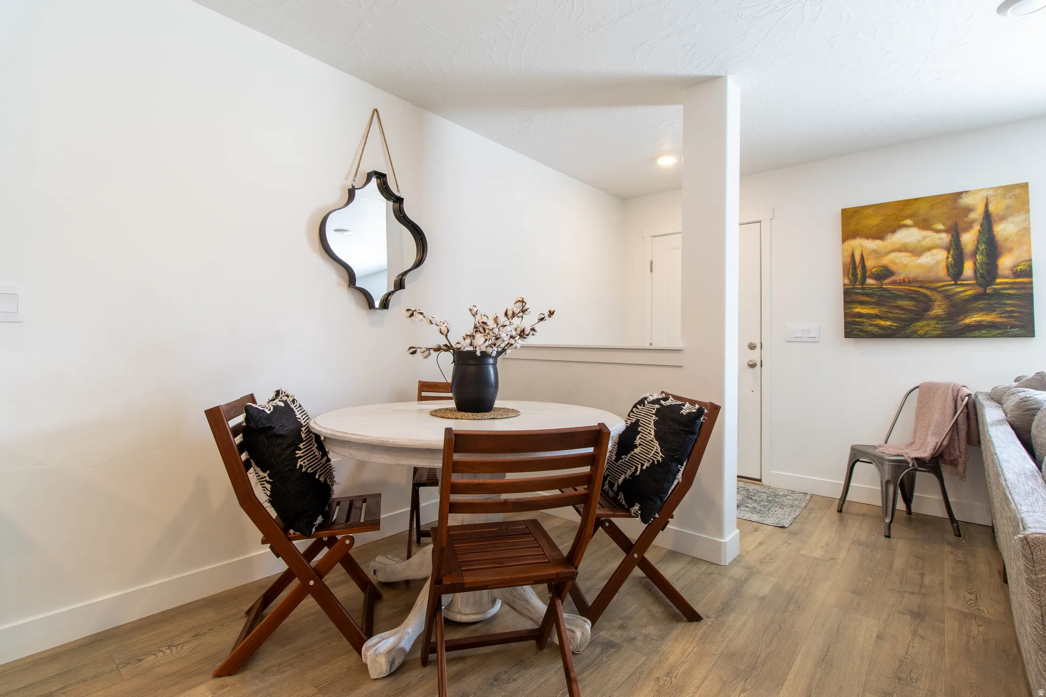 Cozy dining area, front door behind pony wall  with extensive baseboard and premium laminate flooring