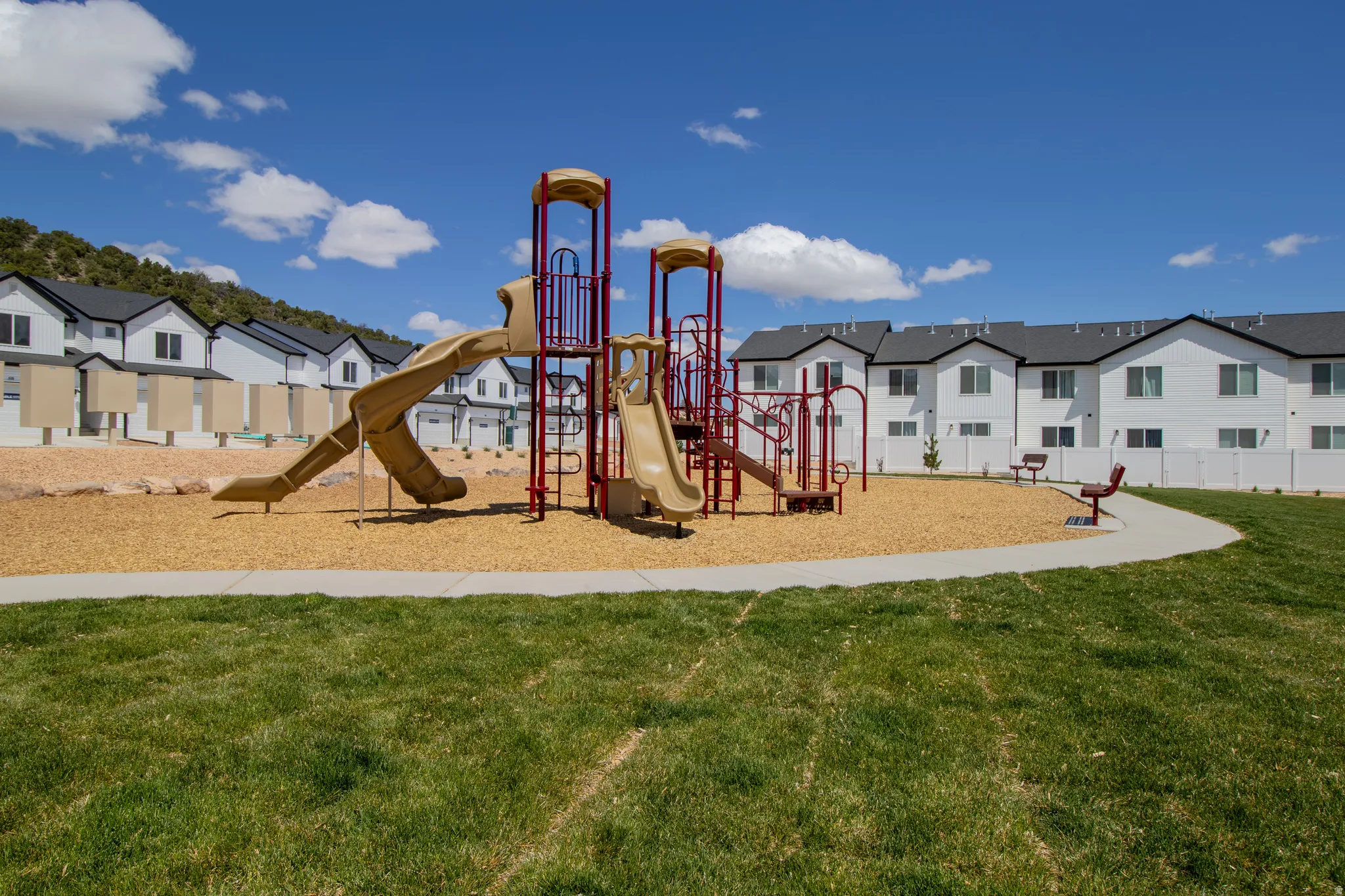 Community playground featuring multiple slides, climbing structures, and benches.