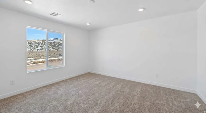 Spacious primary bedroom featuring recessed lighting, a large window that fills the space with abundant natural light, a private ensuite bath, and neutral carpet flooring