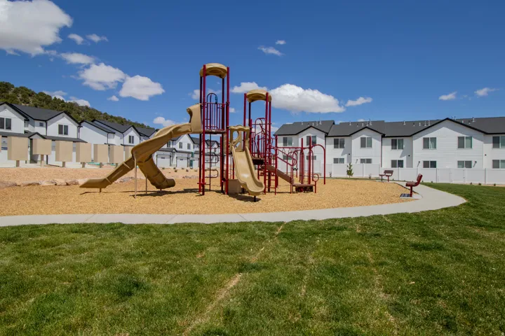 Community playground featuring multiple slides, climbing structures, and benches.