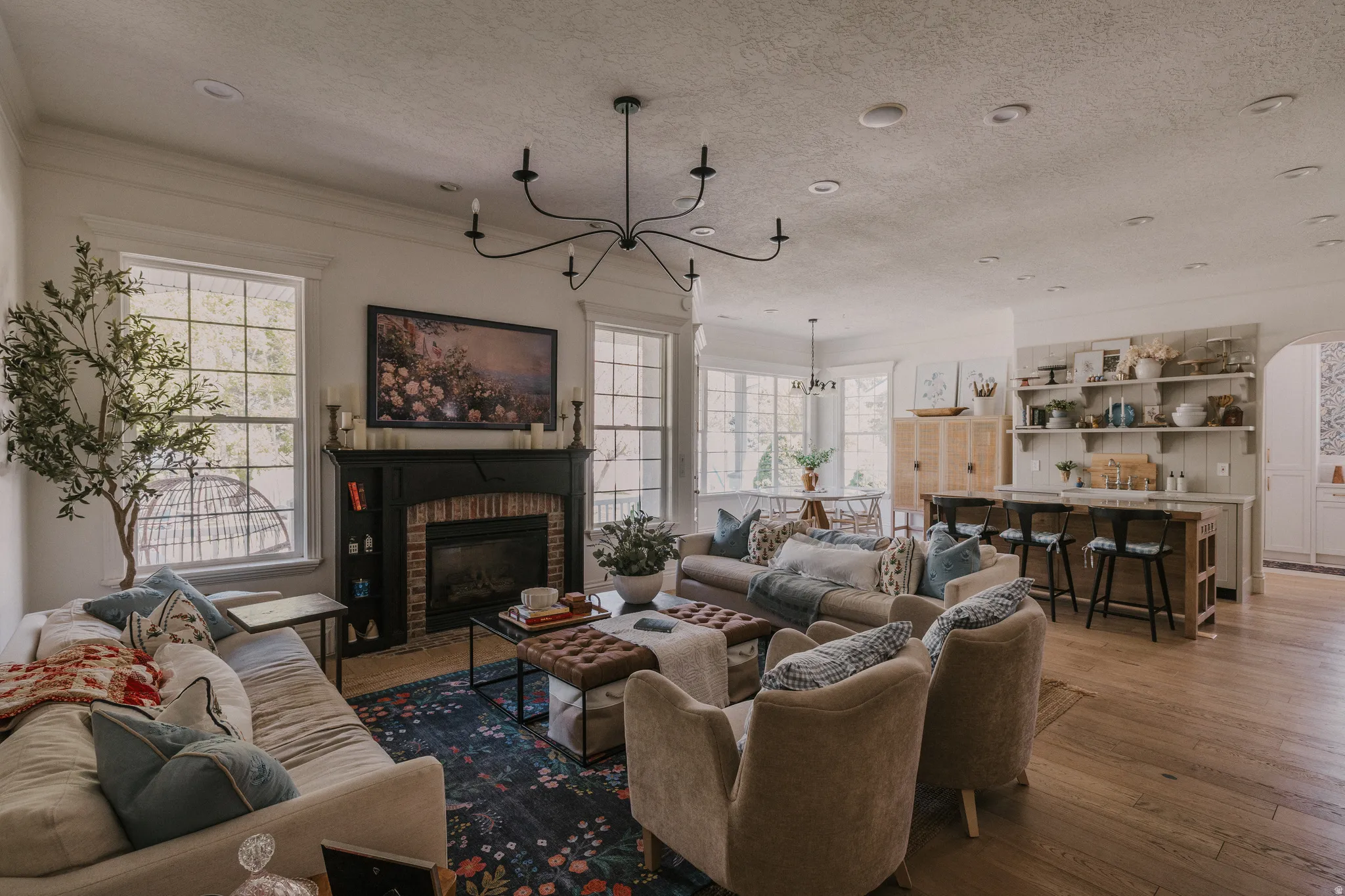Living area featuring wood-type flooring, hanging lights, a fireplace, a textured ceiling, and plenty of natural light
