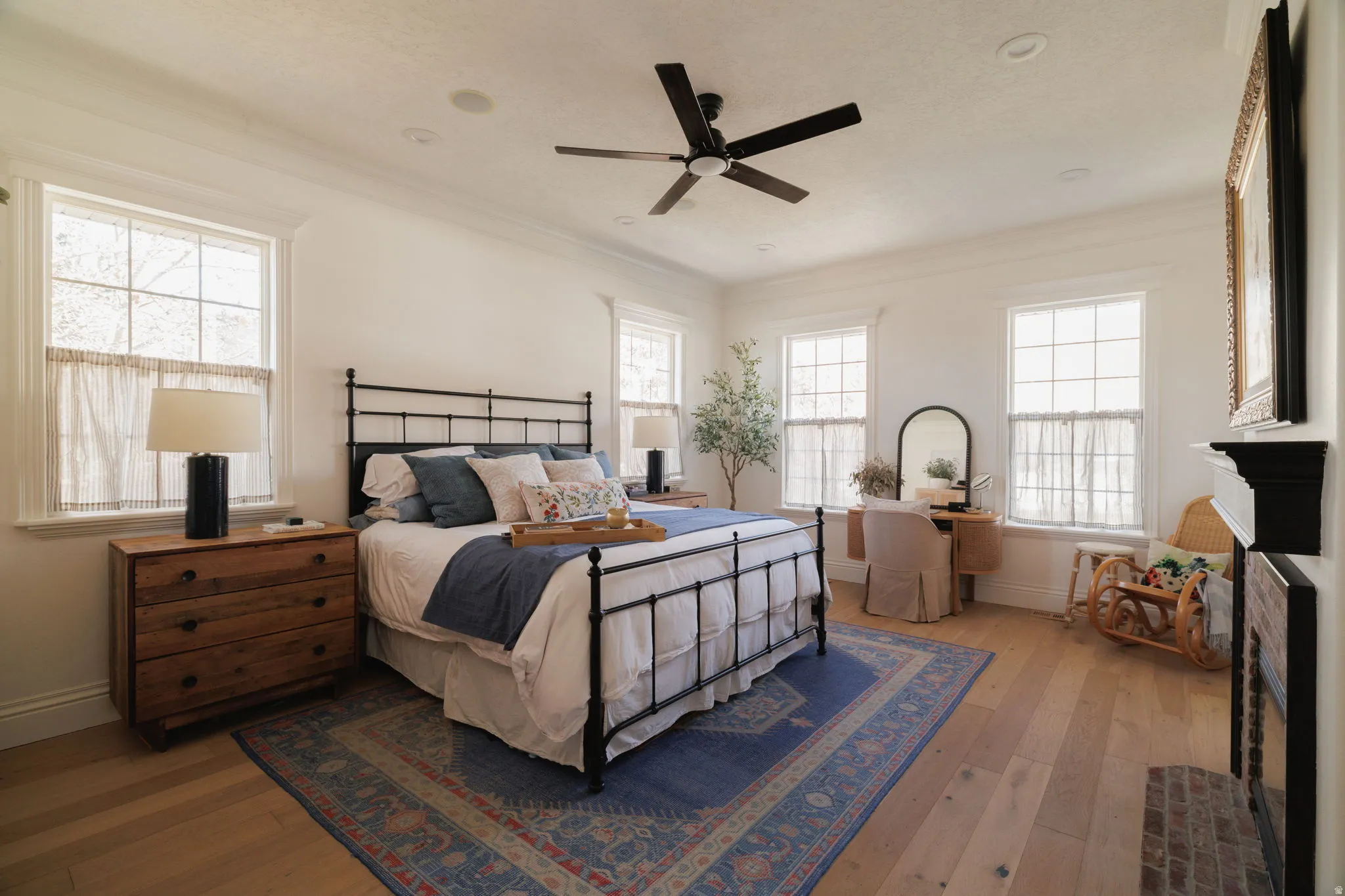 Bedroom featuring a fireplace, light wood-style floors, ceiling fan, and ornamental molding