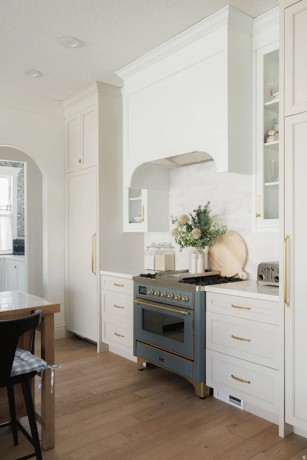 Kitchen featuring white cabinets, glass fronted cabinets, high quality appliances, light wood-style floors, and a textured ceiling