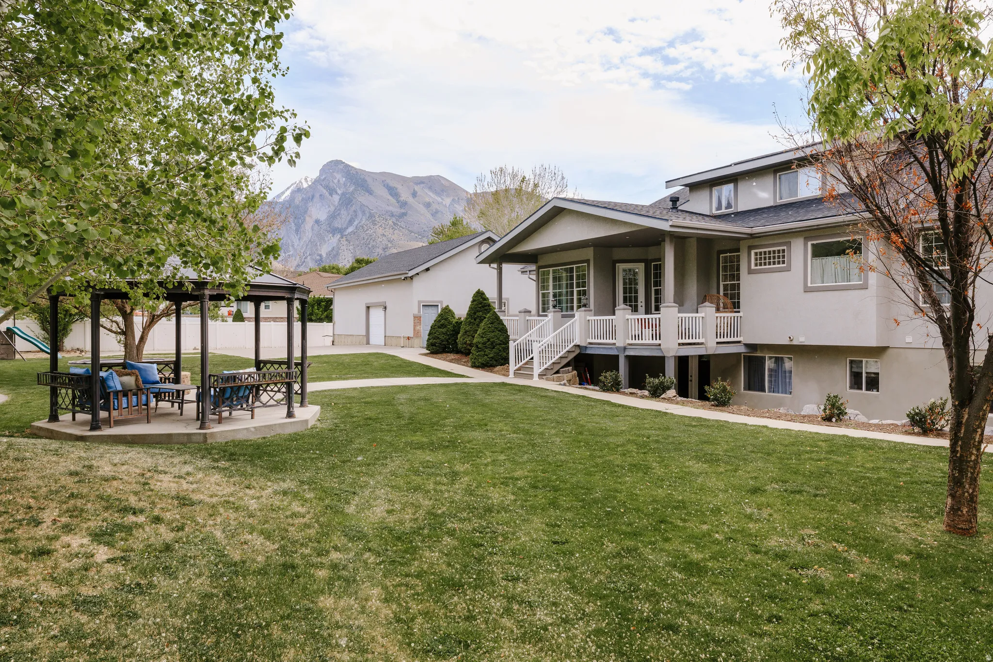 Rear view of house with a lawn, a mountain view, a patio area, and stucco siding