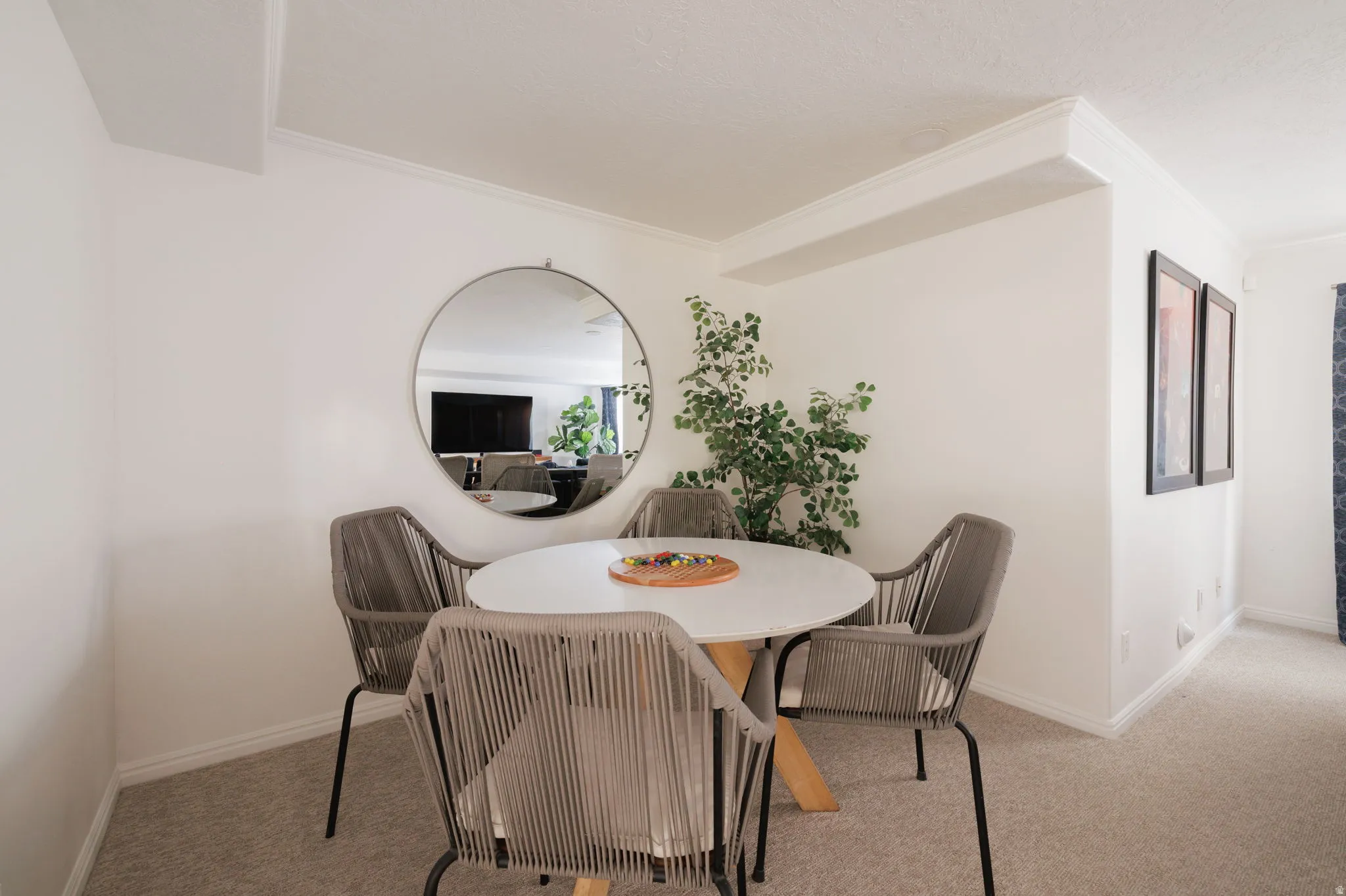 Dining space with ornamental molding and light carpet