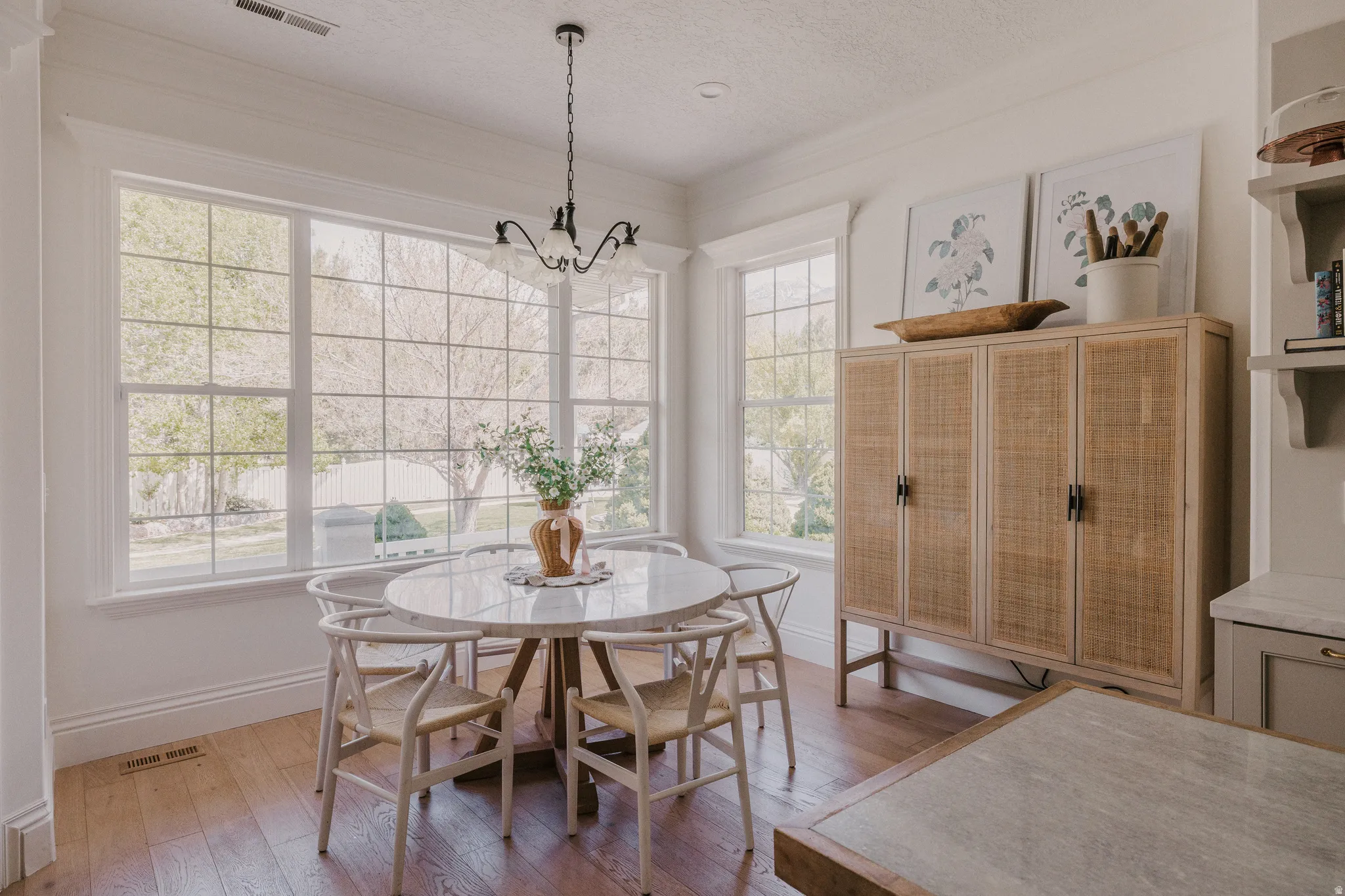 Dining room with light wood-type flooring, suspended lighting, a textured ceiling, and ornamental molding