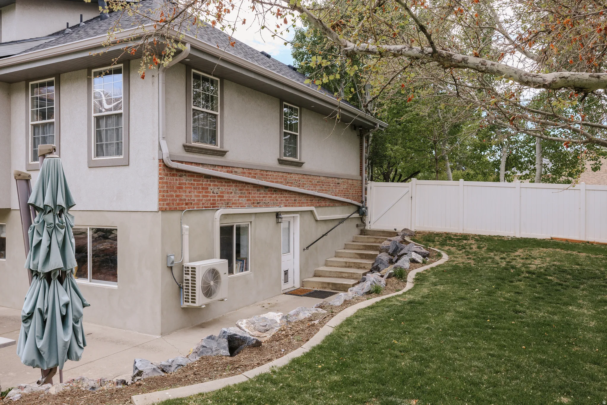Back of house featuring brick siding, stucco siding, a fenced backyard, and a shingled roof