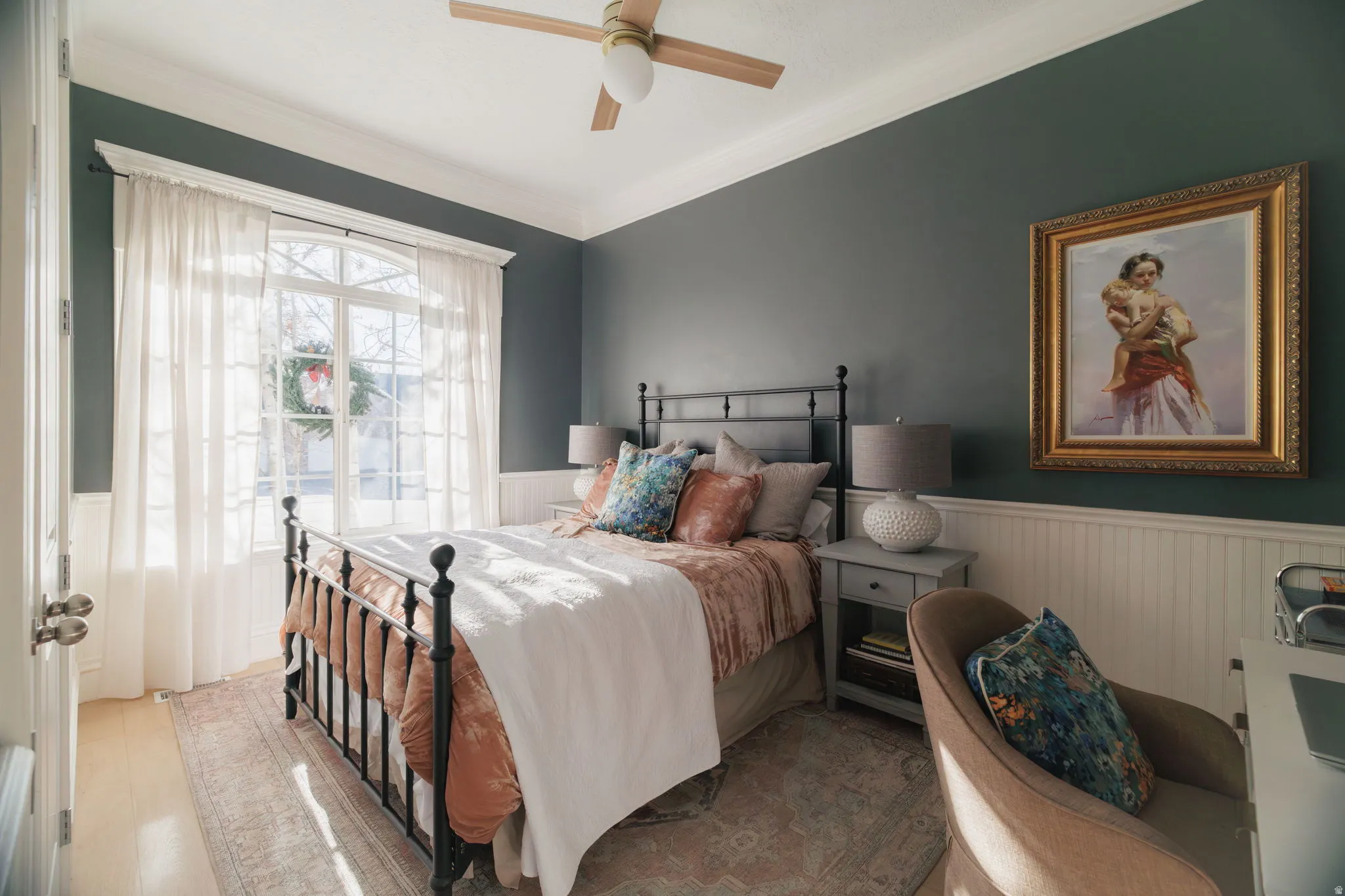 Bedroom with a wainscoted wall, ceiling fan, ornamental molding, and wood finished floors