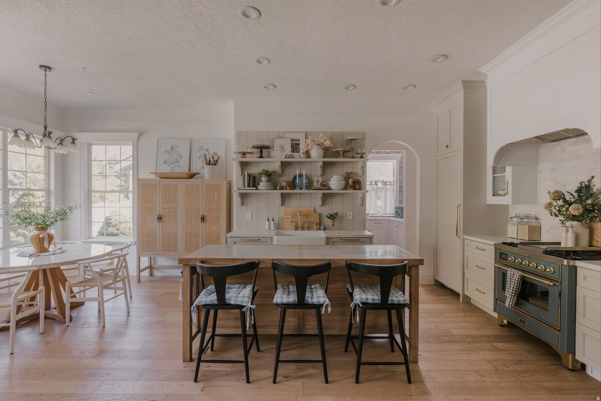 Kitchen featuring range with gas stovetop, white cabinets, light wood-style floors, a textured ceiling, and crown molding