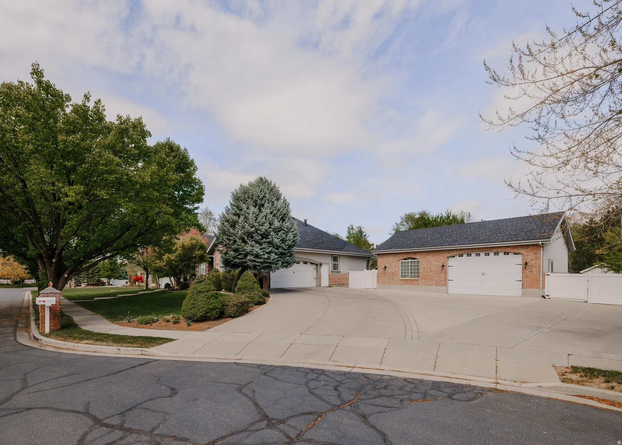 View of front of home with brick siding, a gate, concrete driveway, and a detached garage